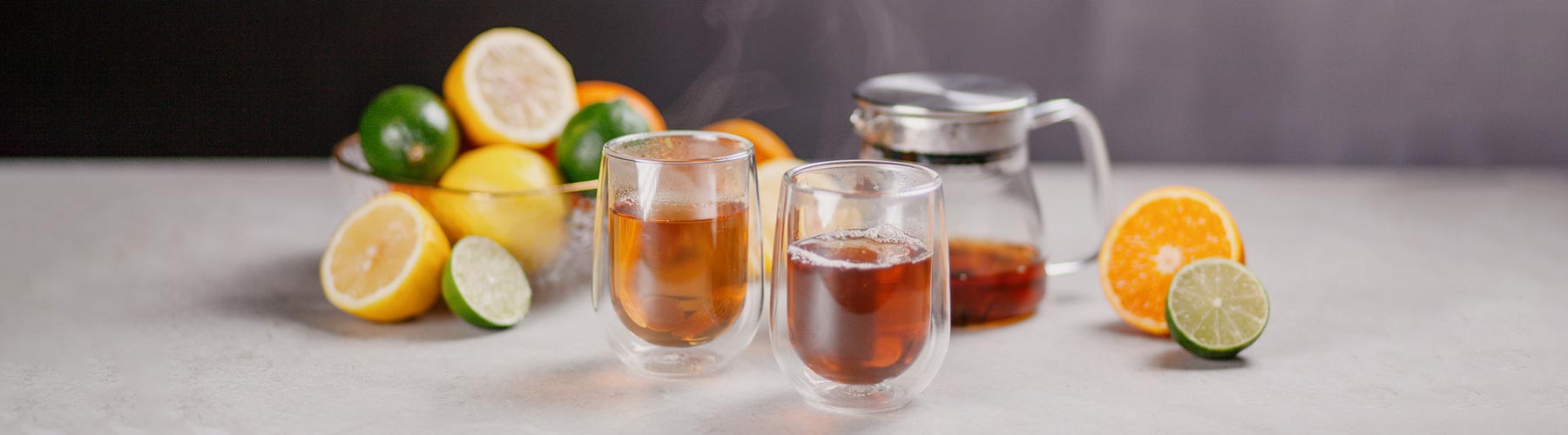 Citrus fruits with glass teapot and 2 glass cups of tea