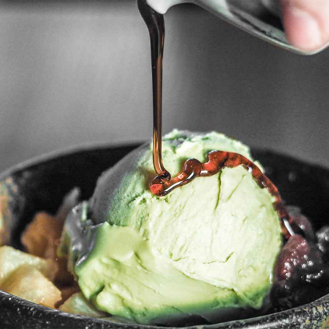 A bowl of matcha ice cream with syrup drizzled on top. 
